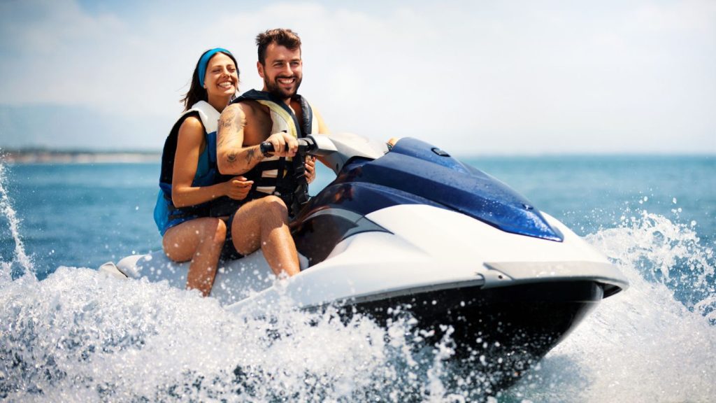 Happy Couple Riding Jet Ski On Water
